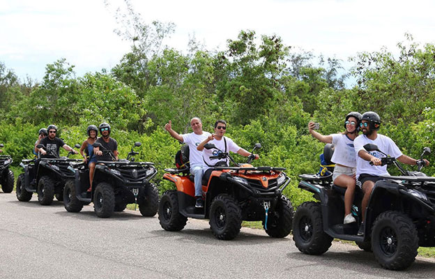 Friends quad biking through villages in Zanzibar